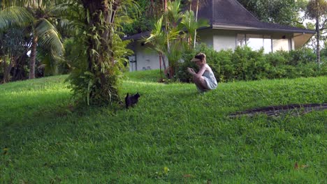 Cat-sprinting-up-a-grassy-hill-towards-a-white-female-squatting-and-filming-then-petting-the-cat