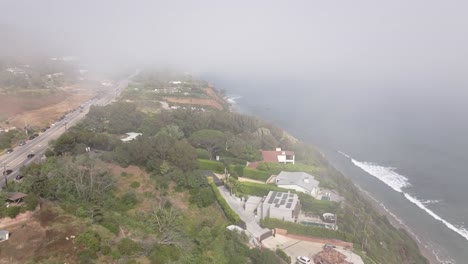 Fog-over-the-Malibu,-California-coastline-on-a-misty-morning---aerial-reveal