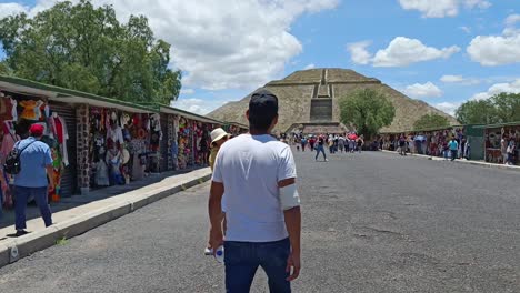 Slow-panning-shot-of-tourists-buying-from-stalls-and-walking-toward-the-Teotihuacan-Pyramid