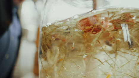 Close-up-shot,-mixing-distilled-gin-inside-a-glass-bottle-with-aromatic-dried-spice-herbs
