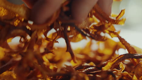 Close-up-shot-of-a-man's-hand-picking-up-yellow-aromatic-dried-spice-herbs-from-a-table