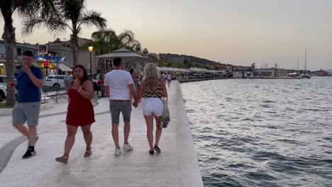 Loving-couple-holds-hands-and-strolls-over-boulevard-of-Argostoli-in-Greece