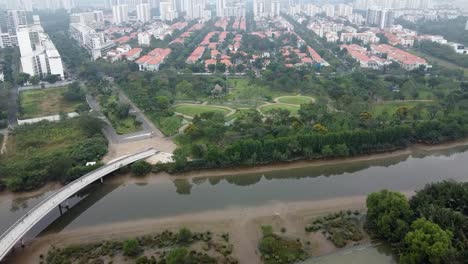 Drohnenvogelperspektive-über-Der-Brücke-über-Den-Fluss-Zum-Leeren-Park-In-Vietnam-An-Einem-Nebligen-Tag