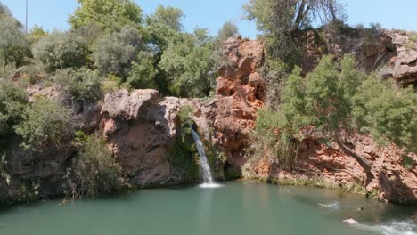 Mannschwan-Taucht-Ins-Wasser-In-Richtung-Eines-Malerischen-Wasserfalls-An-Der-Algarve-In-Portugal,-Drohne