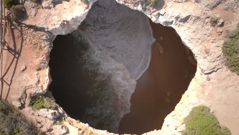 Drone-top-down-view-of-ocean-waves-crashing-in-benagil-sea-cave