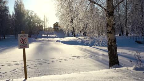 La-Señal-Prohíbe-Caminar-Sobre-Un-Lago-Congelado,-Pero-Hay-Huellas-De-Personas-En-La-Nieve,-Vista-Panorámica-Hacia-La-Derecha.