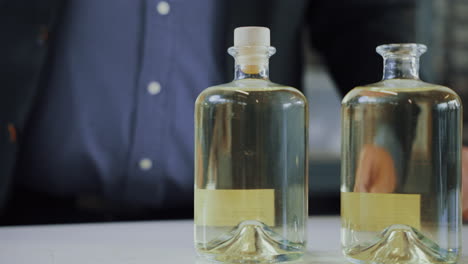 Männlicher-Experte-Setzt-Einen-Verschluss-Auf-Eine-Glasflasche-Mit-Destilliertem-Gin,-Qualitätskontrollprozess-In-Der-Produktion-Einer-Gin-Brennerei