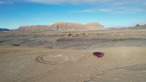 Drone-Shot-of-Red-Van-Moving-Off-Road-in-Desert-Landscape-of-Utah-USA