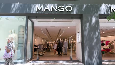 Pedestrians-walk-past-the-Spanish-multinational-clothing-brand-Mango-store-as-shoppers-leave-the-store-in-Spain