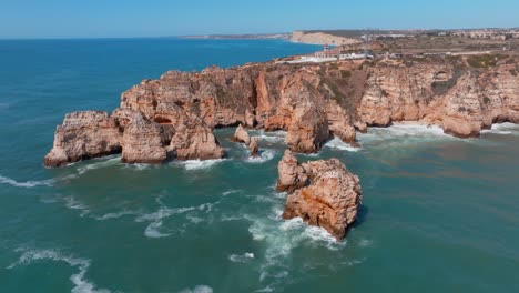 Rocky-ocean-wave-ripples-around-ponta-da-piedade-lagos-algarve-portugal,-aerial-orbit
