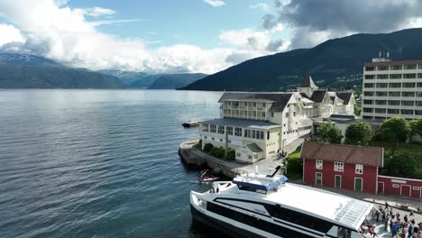 Tourists-in-Balestrand-harbor-and-beautiful-Kviknes-Hotel---Summer-day-seaside-Aerial---Norway