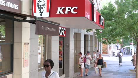 Pedestrians-walk-past-the-American-fast-food-chicken-restaurant-chain,-Kentucky-Fried-Chicken-in-Spain
