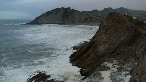 Ocean-waves-crash-on-angled-cliffs-flysch-rocks-at-itzurun-beach-spain