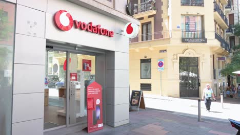 Citizens-walk-past-the-British-multinational-telecommunications-corporation-and-phone-operator,-Vodafone,-store-in-Spain