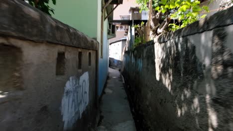 Walking-through-narrow-grungy-depressing-alleyway-with-graffiti-through-houses-during-daylight-in-Southeast-Asian-destination