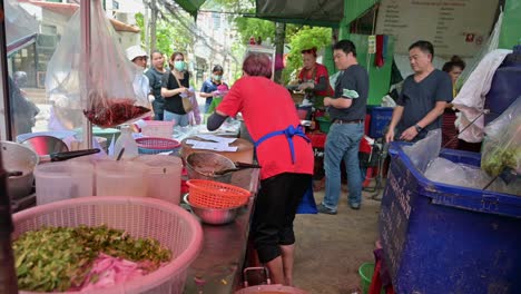 Un-Famoso-Vendedor-Ambulante-Local-Recibiendo-Pedidos-De-Pollo-Y-Cerdo-A-La-Parrilla-En-Las-Calles-De-Bangkok,-Tailandia