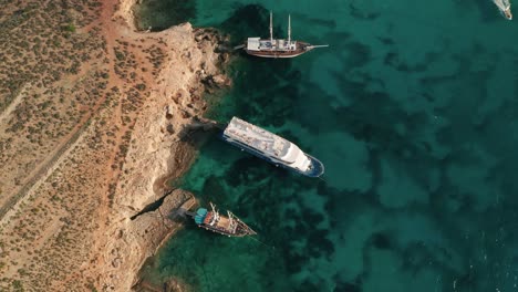 Aerial-drone-footage-of-several-boats-anchoring-in-Malta's-magnificient-Blue-Lagoon,-renowned-for-its-mesmerizing-clear-waters