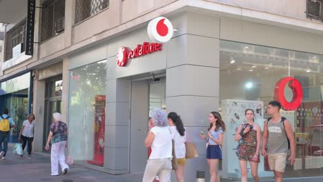 Pedestrians-walk-past-the-British-multinational-telecommunications-corporation-and-phone-operator,-Vodafone,-store-in-Spain