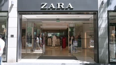A-shopper-leaves-the-Spanish-multinational-clothing-design-retail-company-by-Inditex,-Zara,-store-as-pedestrians-walk-past-it-in-Spain