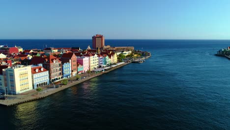 Aerial-panoramic-view-of-bright-cheerful-buildings-of-curacao-at-sunrise,-looking-out-into-ocean