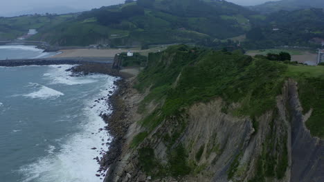 Aerial-pan-tilt-up-reveals-grassy-cliffside-edges-above-itzurun-beach