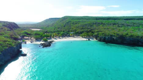 Drone-rises-above-secluded-white-sandy-tropical-beach-cove,-curacao