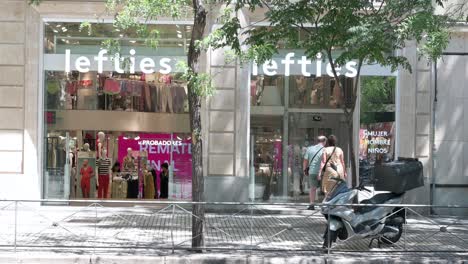 People-walk-past-the-Spanish-fashion-brand-owned-by-Inditex,-Lefties,-store-in-Spain