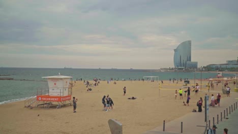 Atemberaubendes-Video-Von-Menschen,-Die-Am-Sandstrand-In-Barcelona-Spazieren-Gehen-Und-Spielen