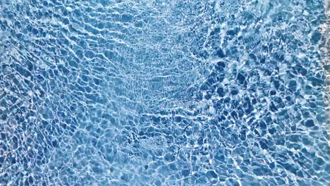 Water-surface-texture,-Slow-motion-looping-clean-swimming-pool-ripples-and-wave,-Refraction-of-sunlight-top-view-texture-sea-side-white-sand,-sun-shine-water-loop-background