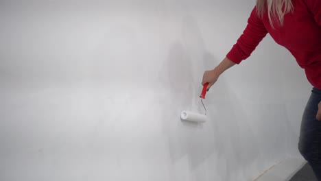 the-woman-painting-walls-with-roller-equipment-while-moving-in-apartment.-Renovating-new-house-and-improvement-concept
