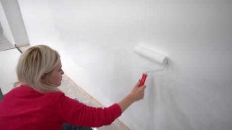 the-woman-painting-walls-with-roller-equipment-while-moving-in-apartment.-Renovating-new-house-and-improvement-concept