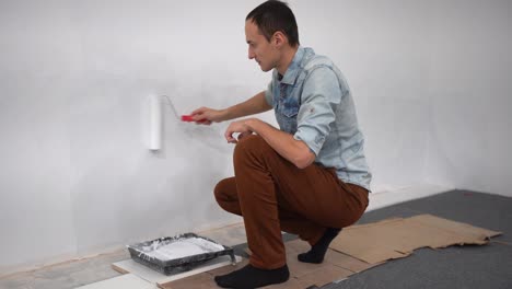 Male-decorator-painting-a-wall-with-white-color.