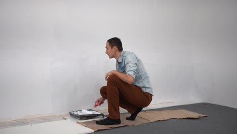 Male-decorator-painting-a-wall-with-white-color.