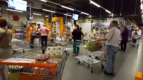 People-waiting-with-products-in-shopping-trolley-at-the-checkout-counter-of-the-Colruyt-supermarket-in-Brussels,-Belgium