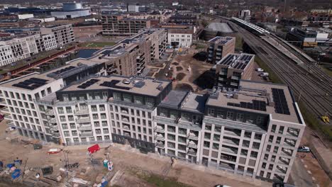 Fast-aerial-ascend-revealing-facade-and-construction-site-of-luxury-Kade-Zuid-apartment-complex-at-riverbank-of-river-IJssel-between-train-tracks-and-recreational-port