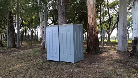 travelling-out-of-grey-portable-bathroom-surrounded-by-trees-on-a-sunny-day