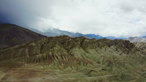 Cámara-Aérea-De-Drones-Avanzando-Sobre-Las-Montañas-De-Leh-Ladakh-Con-El-Himalaya-En-El-Fondo-Y-Rodeada-De-Nubes-Por-Todos-Lados