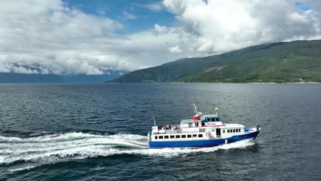 Tourists-enjoying-themselves-onboard-sightseeing-boat-in-Sognefjorden-Norway---Aerial-from-side-of-boat-moving-upwards-and-turning-around-to-mountain-landscape