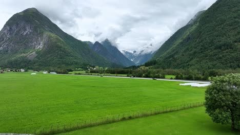 Aerial-flying-in-between-flags-on-rooftop-of-Fjaerland-Glacier-Museum-with-Boyabreen-glacier-seen-in-background-valley---Norway-Sogn-60-fps