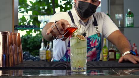 Latin-mexican-bartender-mixology-mix-red-shot-of-cocktail-drink-mojito-tequila-sunrise-mezcal-lemon-gin-slow-motion-at-beach-restaurant-bar