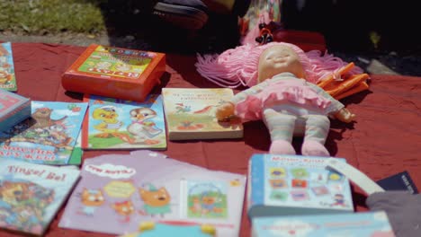 A-girl-doll-with-pink-hair-and-books,-games-and-magazines-for-sale-at-garage-sale