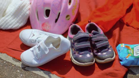 Purple-and-white-child-pair-of-shoes-and-pink-bike-helmet-on-a-garage-sale