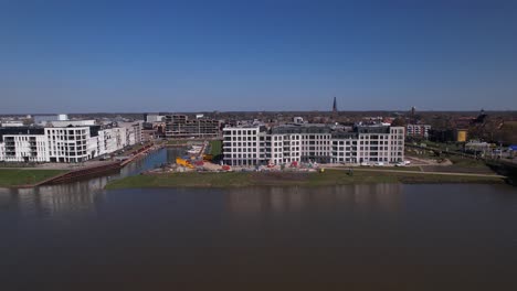 Meadow-floodplains-aerial-reveal-on-Kade-Zuid-apartment-complex-new-housing-construction-project-part-of-urban-development-in-Zutphen-with-Noorderhaven-neighbourhood-along-river-IJssel