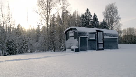 A-warmly-dressed-woman-coming-out-of-a-cabin-into-a-snow-covered-winter-landscape