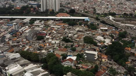 Aerial-top-down-shot-showing-slum-area-of-Jakarta-and-traffic-on-busy-highway-during-cloudy-day