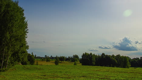 Ruhiger-Zeitraffer-Von-Grünen-Feldern-Und-Bäumen-Mit-Sonnenaufgang,-Der-Hinter-Rollenden-Wolken-Kaum-Sichtbar-Ist