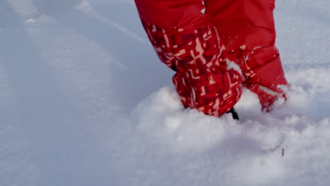 Die-Beine-Einer-Person-In-Roten-Schneeschutzhosen,-Die-Durch-Hohen-Schnee-Geht