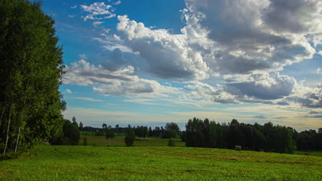 Timelapse-of-Clouds-Drifting-Over-a-Serene-Green-Landscape,-the-sun-disappearing-offscreen