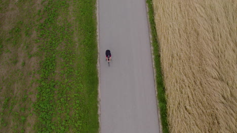 Top-view-tracking-shot-of-man-cycling-on-country-road