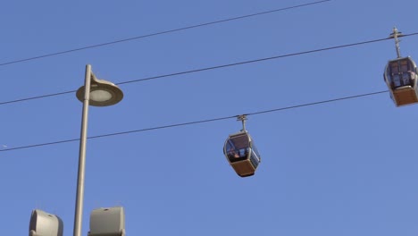 Low-angle-shot-of-Funicular,-cable-cars-moving-over-Vila-Nova-de-Gaia,-Portugal-for-tourists-sightseeing-on-a-sunny-day